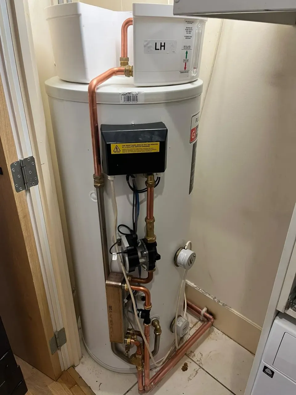 Hot water cylinder with feed tank above and connected pump and copper pipework