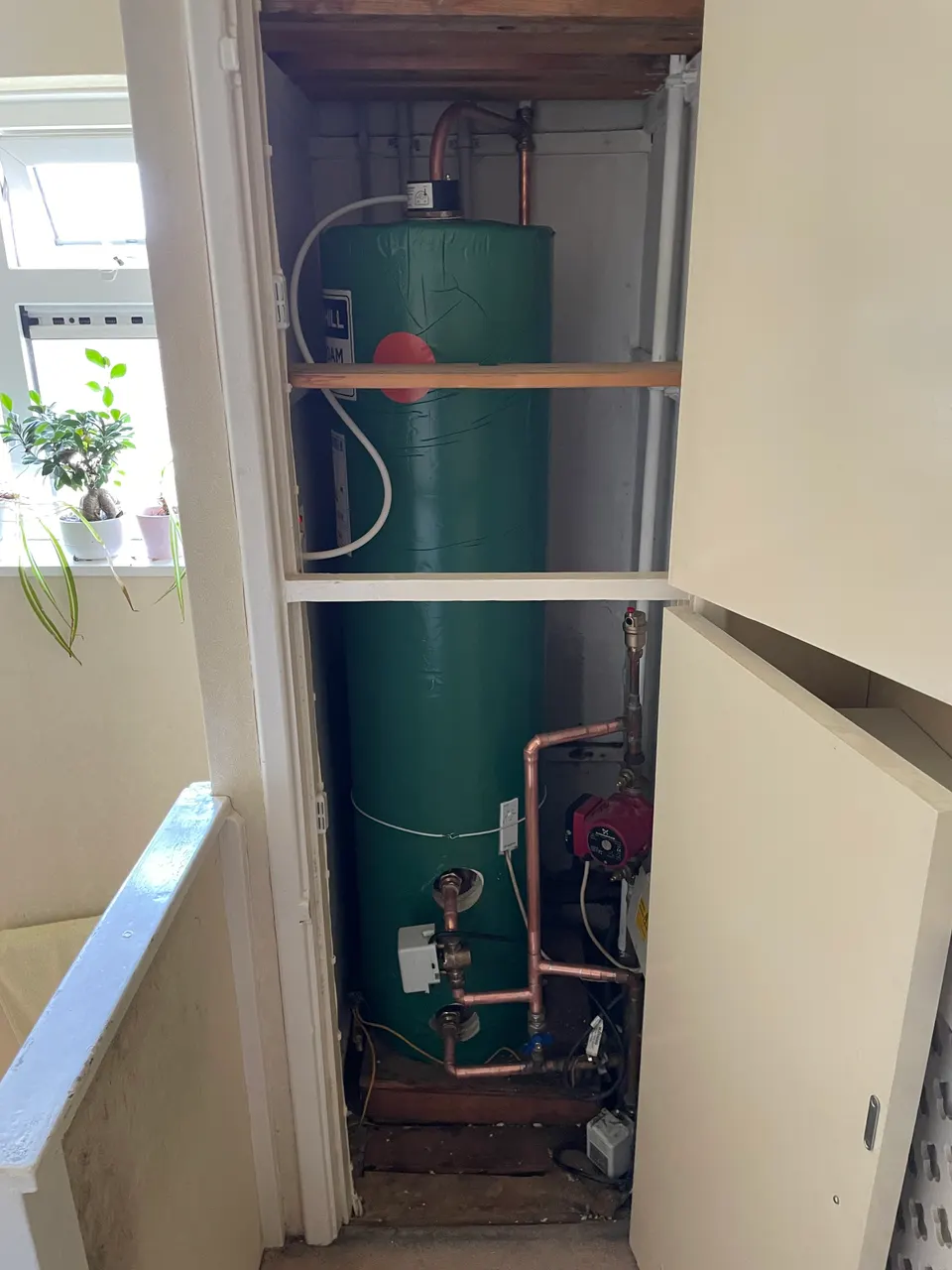 Insulated hot water cylinder with connected pump and copper pipework